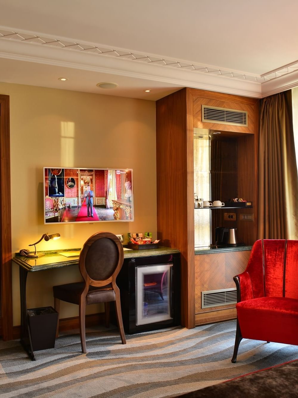 Red velvet armchairs by a round table under soft light in deluxe room at Warwick Ankara