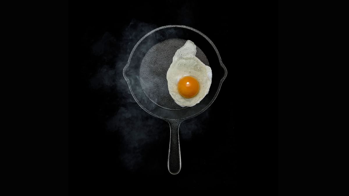 Egg frying in a skillet, against a black background featuring Sydney Bed & Breakfast at Crown Hotels
