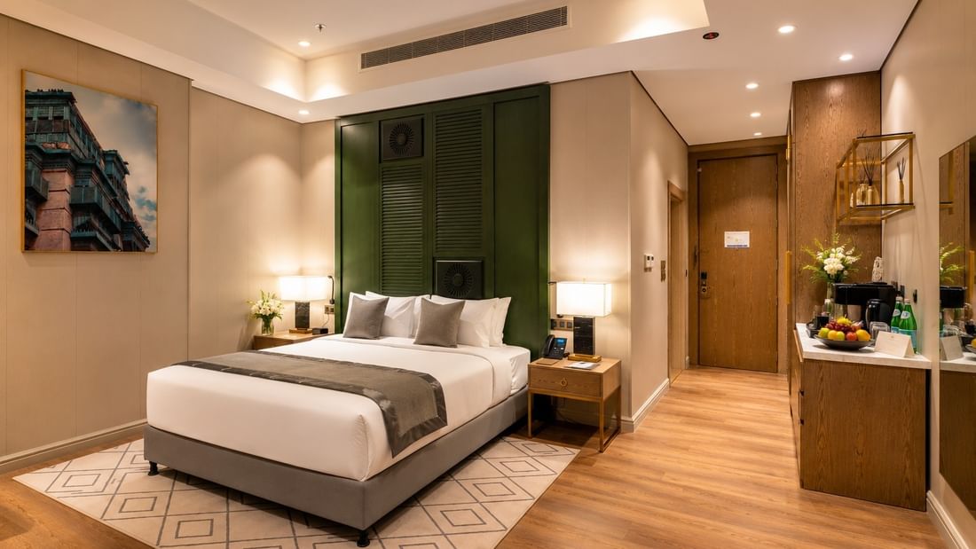 Executive Suite featuring king bed and a minibar counter beside a wooden hallway door at Naviti by Warwick Jeddah