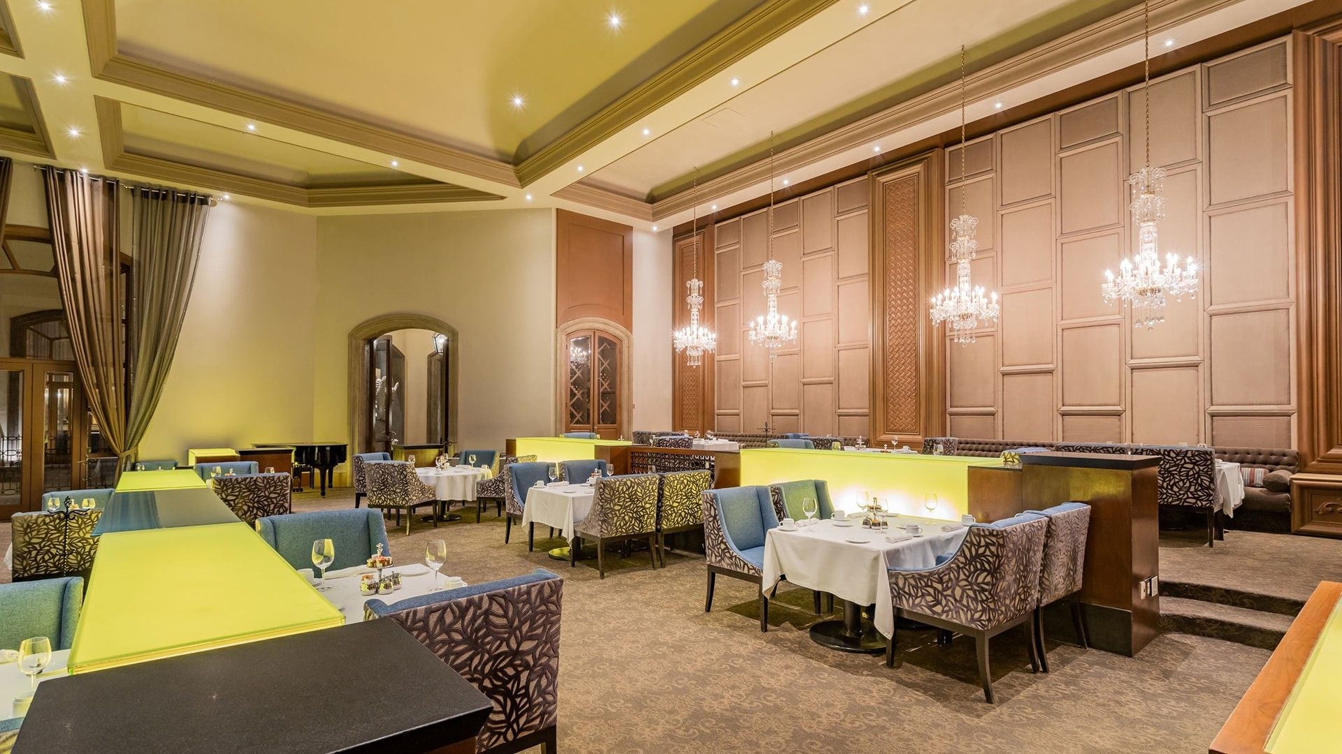 Tierra Mía luxury dining hall featuring ornate wall panels and multiple glowing glass chandeliers at Quinta Real Monterrey