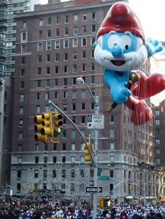 Large blue Smurf parade balloon floating through the streets of New York City buildings near Warwick New Yok
