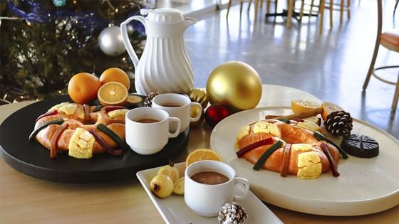Desayuno festivo con pan dulce, café, naranjas frescas y adornos festivos en La Pérgola, Araiza Palmira 