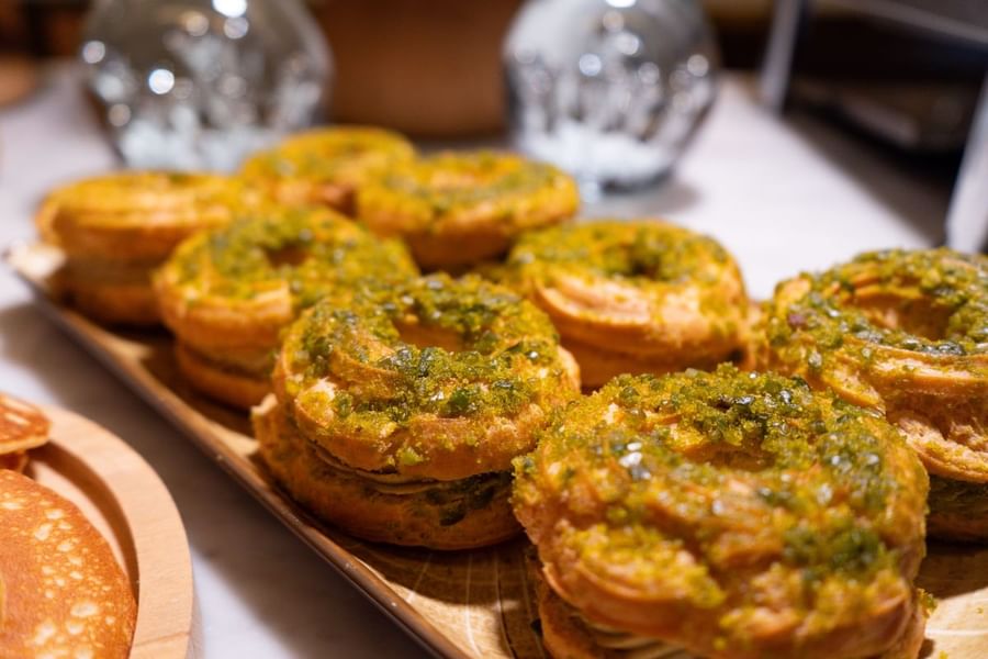 Des baguettes grillées garnies de pesto vert, présentées sur une planche de service en bois chez Warwick Paris Champs-Élysées