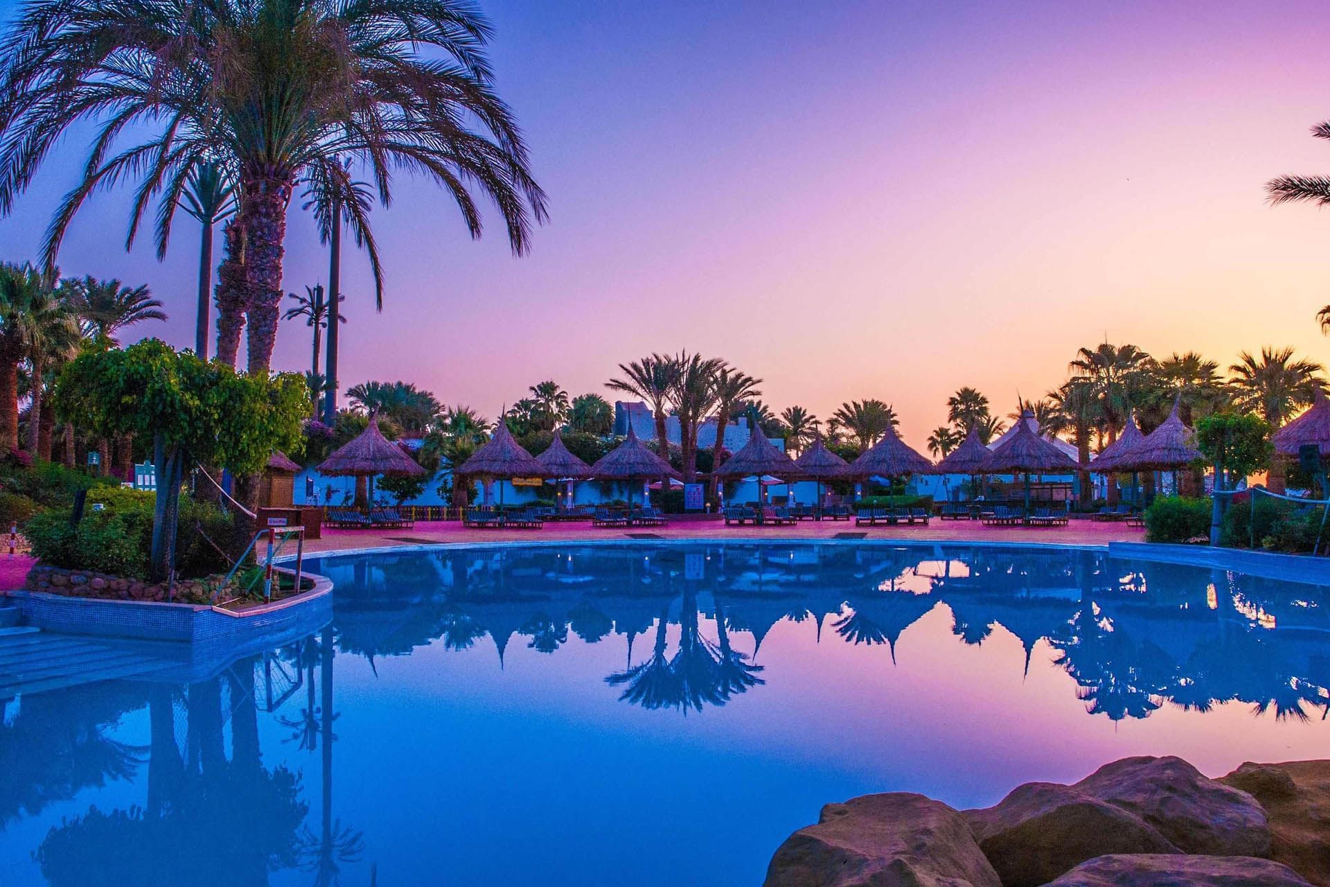 Pickalbatros Golf Beach Resort, All Inclusive Resort Sharm El Sheikh, with cabanas and a pool reflecting vibrant dusk skies