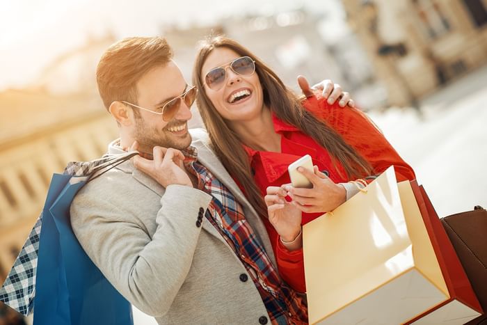 Couple happily holds shopping bags & enjoy near Hotel Grand Chancellor