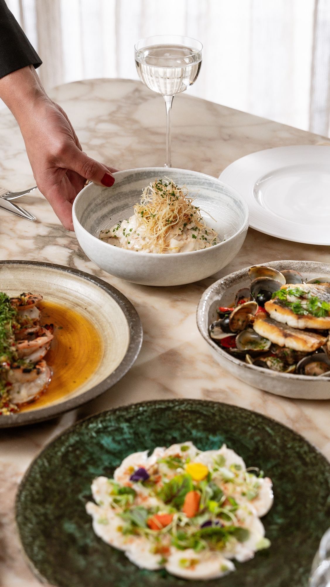 Dining table arranged with food plates & drinks in May Fair Kitchen at The May Fair Hotel