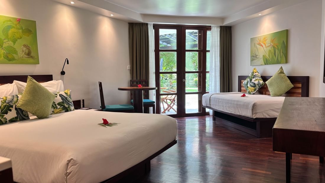 Two garden view rooms at Warwick Fiji in Korolevu with beds, chairs, and artwork.