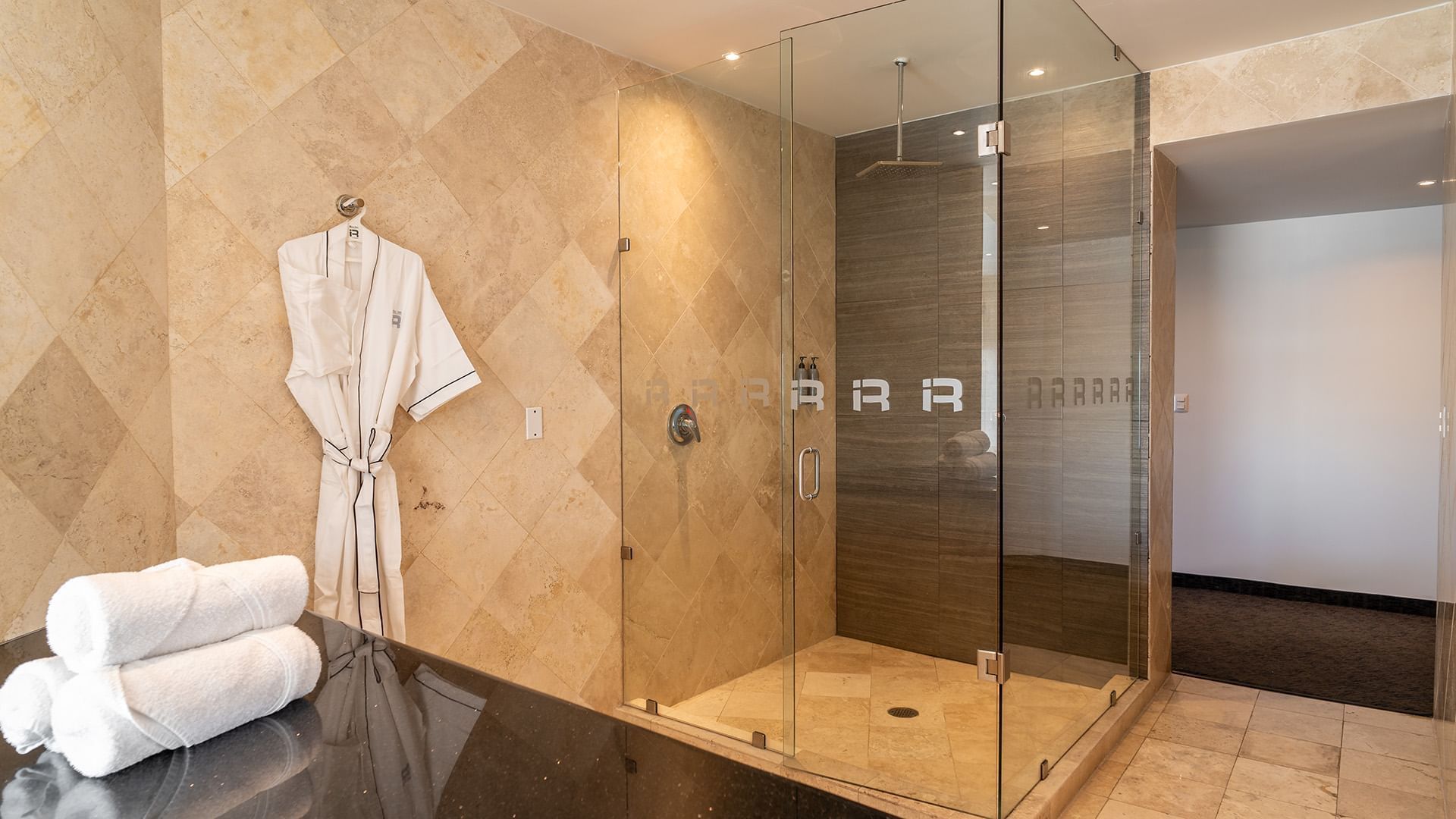 King Presidential Suite bathroom with a glass-enclosed rain shower, and a white bathrobe at Real Inn Tijuana