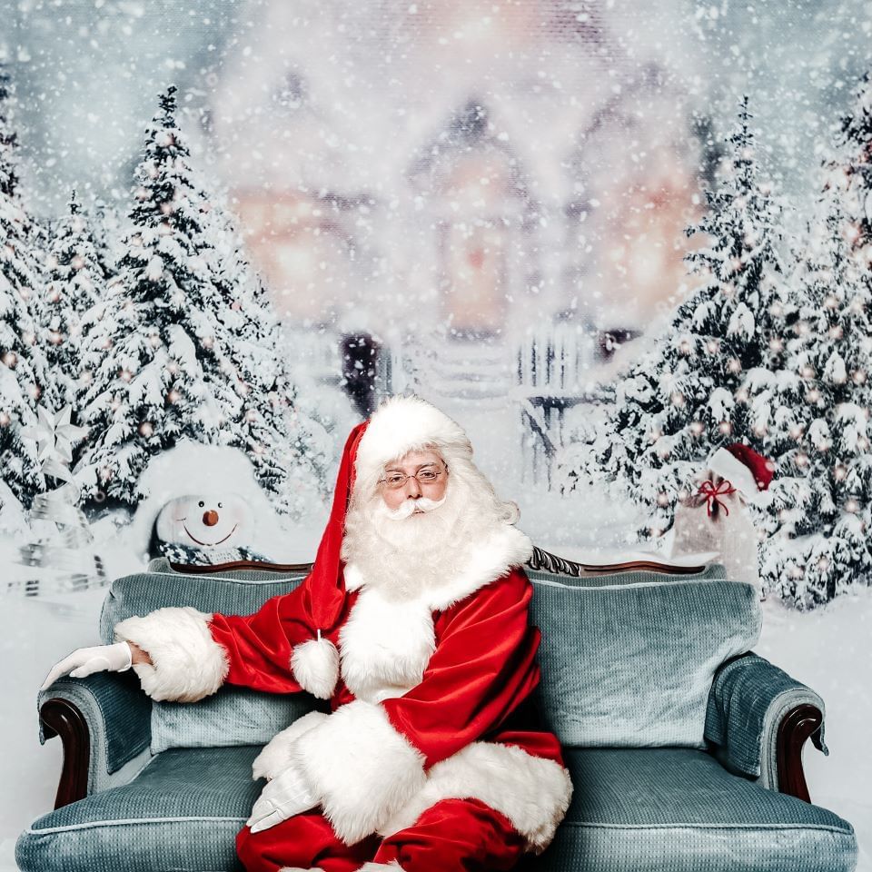 Santa Claus posing in front of a snowy background at Blackcomb Springs Suites