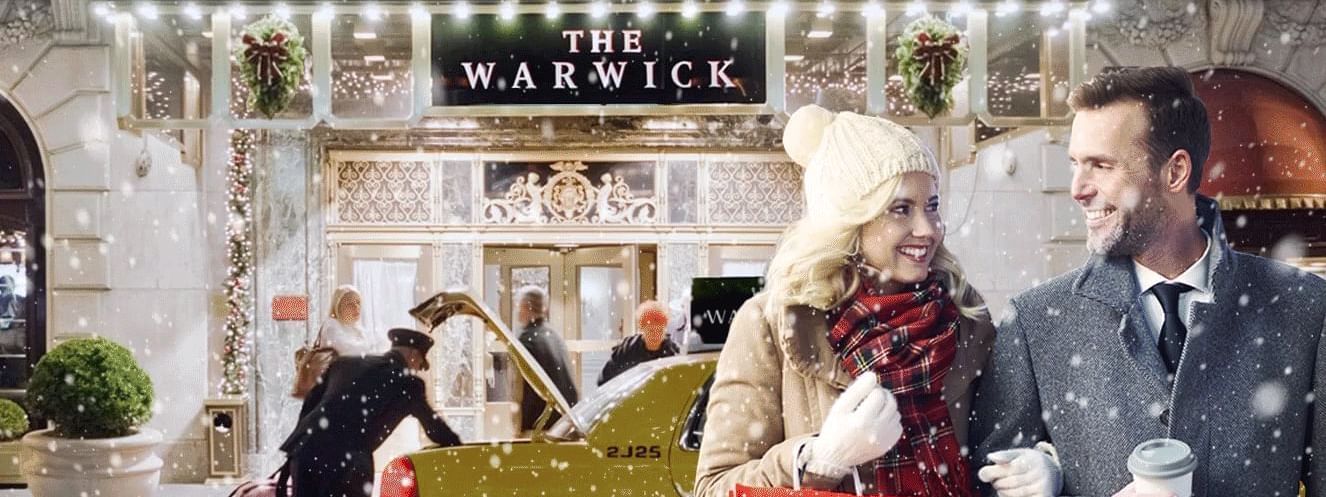 Couple in front of the Warwick New York with a Macy's bag