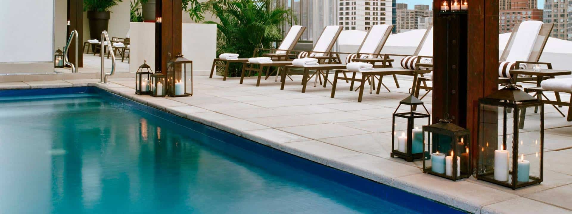 a pool with lounge chairs and lanterns
