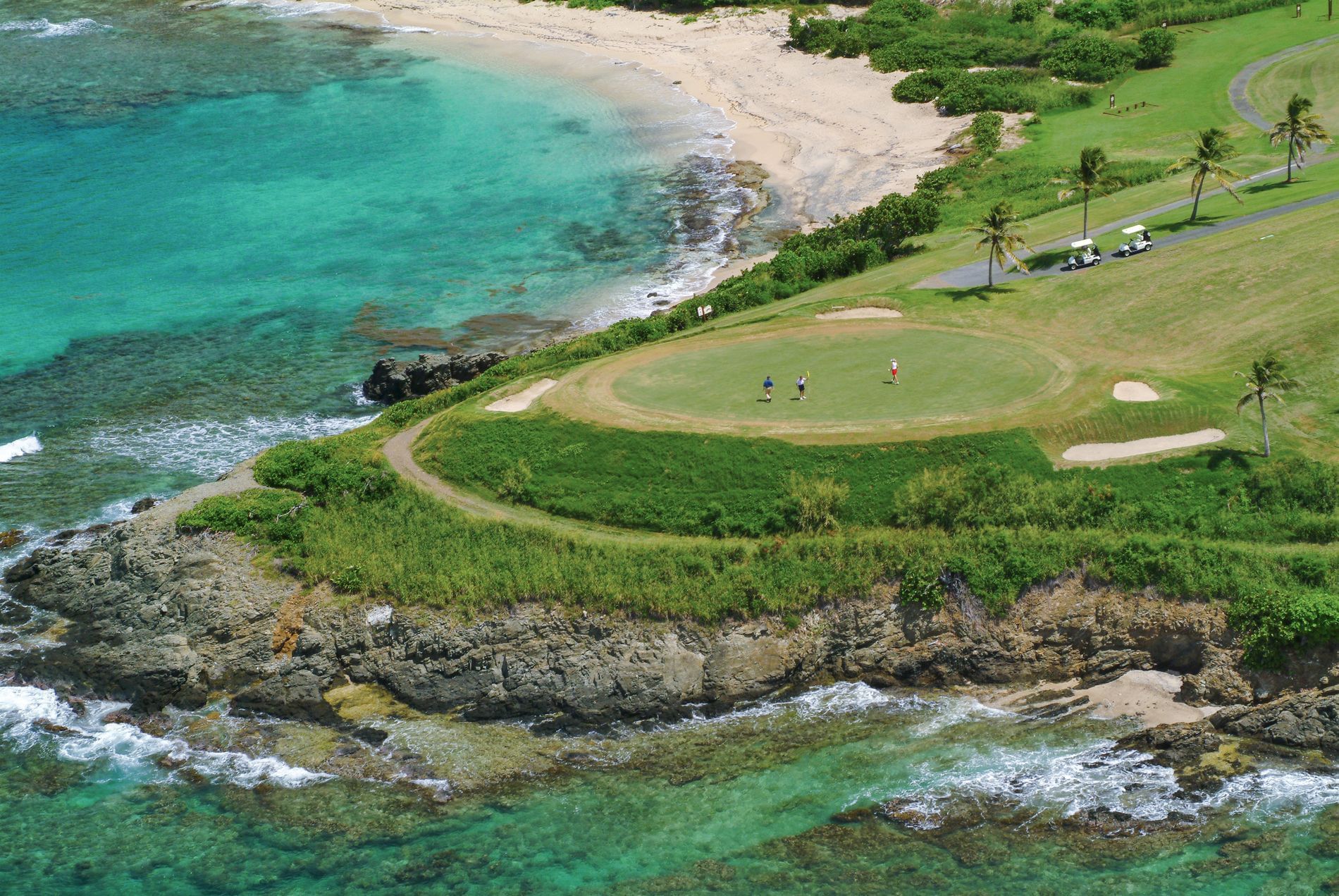 Aerial view of a golf course by the ocean near The Buccaneer Resort St. Croix
