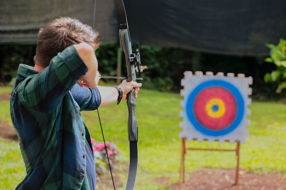 Person aiming an arrow at a target on a sunny outdoors in El Silencio Lodge & Spa