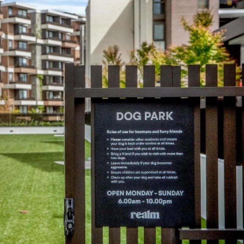 Sign in front of dog park entrance lists rules and hours of operation.