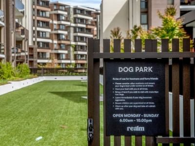 Sign in front of dog park entrance lists rules and hours of operation.