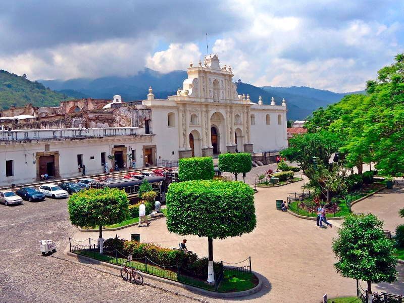 Antigua Guatemala Cathedral, with cars and trees under a cloudy sky near Casa Santo Domingo