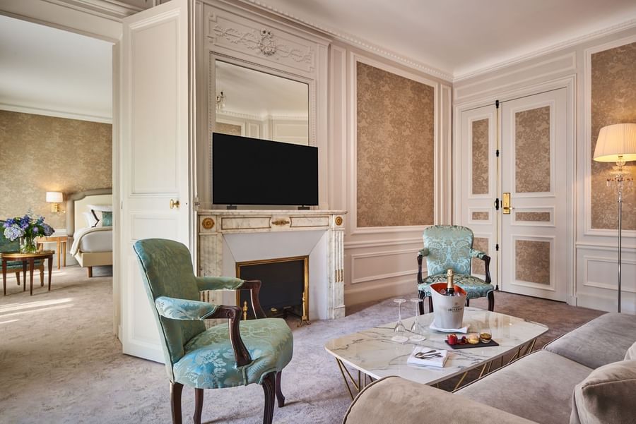 TV lounge with plush sofa and doorway to bedroom in Prestige Suite – Rue de la Paix View at Hotel Westminster Paris