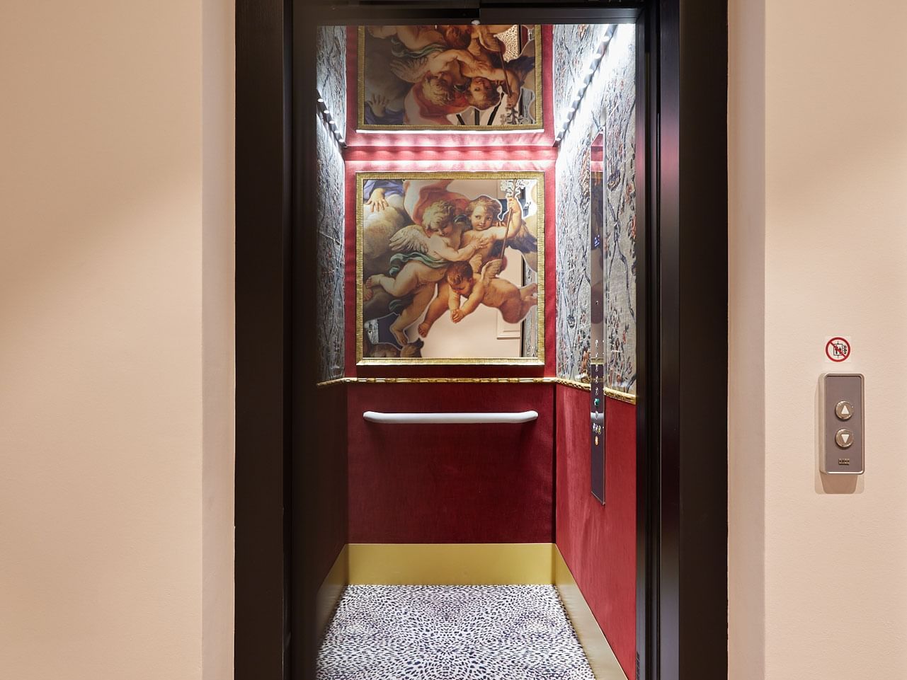 Open elevator doors with leopard print floors, red walls, and framed artwork inside the shaft.