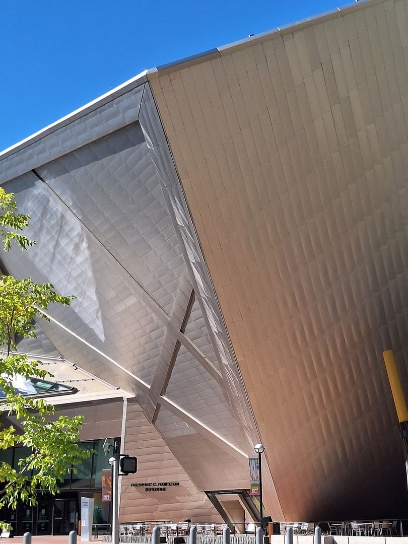 Frederic C. Hamilton Building by a green tree under a clear blue sky near Warwick Denver