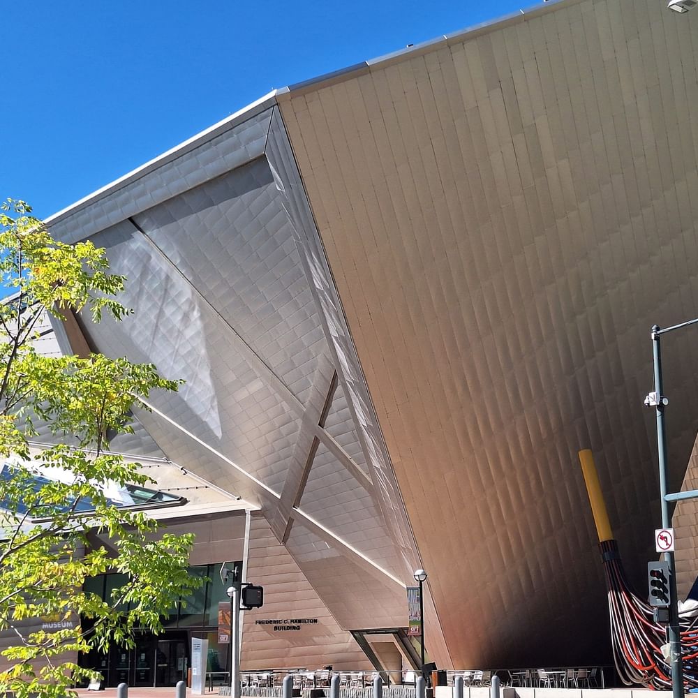 Frederic C. Hamilton Building by a green tree under a clear blue sky near Warwick Denver