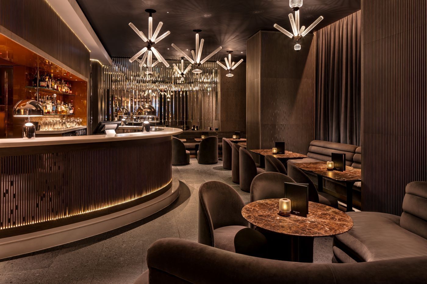 Elegant lounge with modern furniture, dim lighting, and stylish bar counter at The May Fair Bar