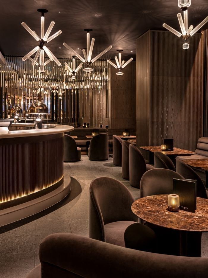 Elegant lounge with modern furniture, dim lighting, and stylish bar counter at The May Fair Bar