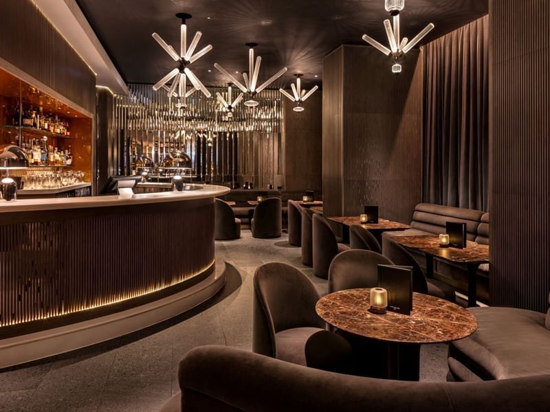 Elegant lounge with modern furniture, dim lighting, and stylish bar counter at The May Fair Bar