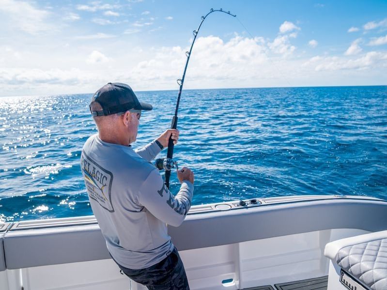 Hombre pescando en la cubierta de un barco con caña en mano cerca de Los Altos Resort