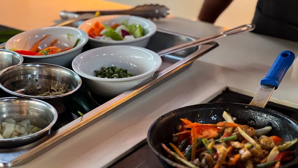 Bowls of assorted vegetables on a tray and a pan with stir-fried veggies at KanaVata Restaurant in Nadi.