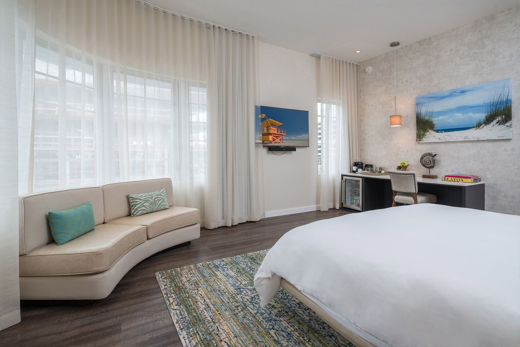 A wide view of a hotel room with a large bed, a sofa, a TV, and a desk.