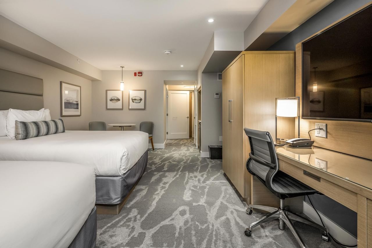 View of two beds, tv, work desk and sitting area in our Coast Accessible Room