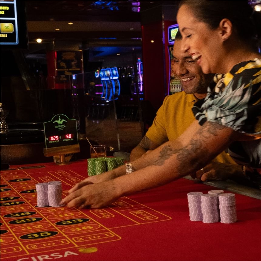 Pareja sonriente juega a la ruleta y coloca fichas sobre una mesa roja cerca de Megapolis Hotel Panama