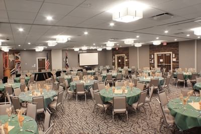 Large banquet hall set up with numerous round tables with green tablecloths at Buffalo Bill Village