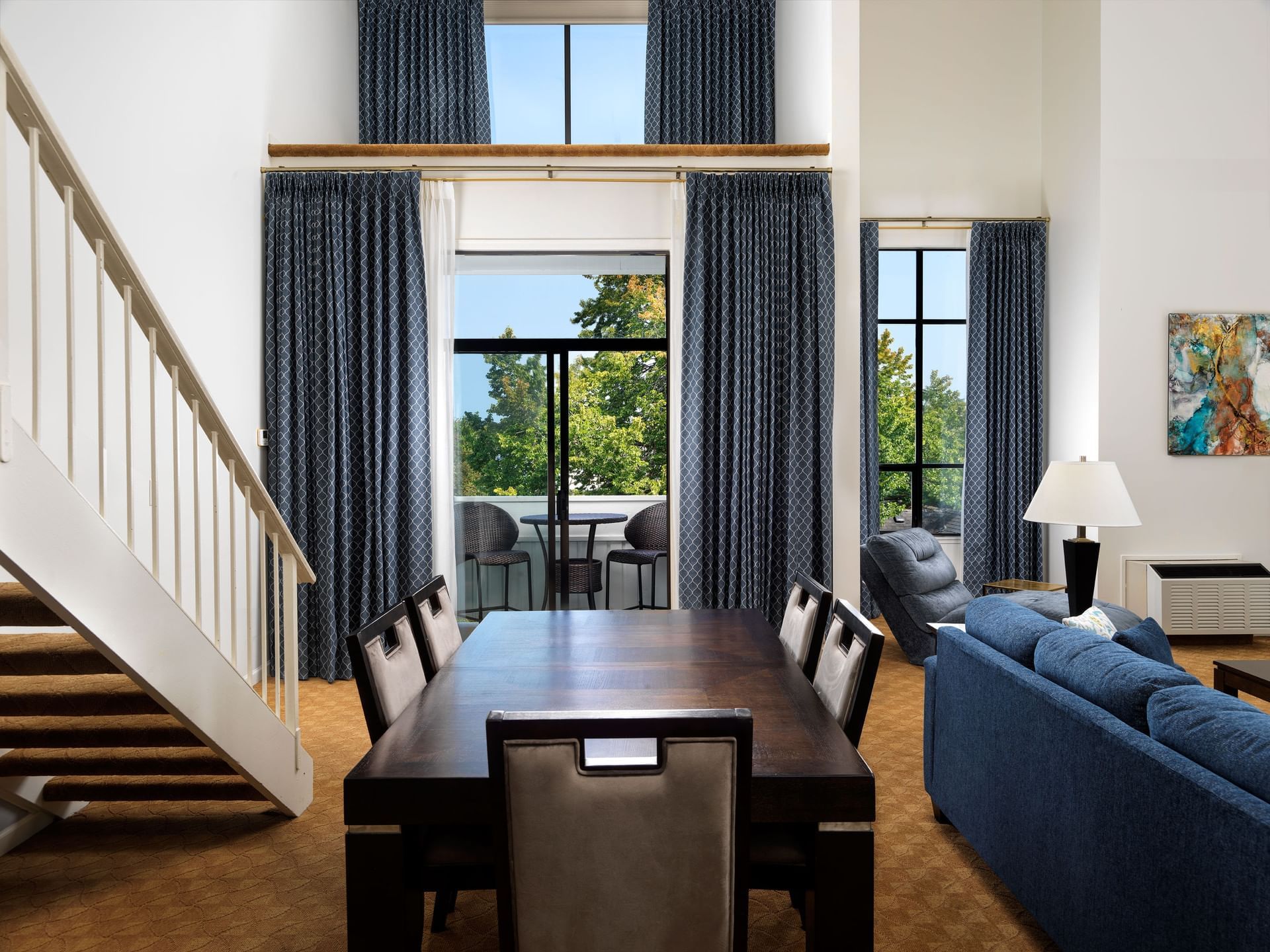 Living room featuring staircase, dining table & blue couch in Grand Dorset Suite at Huntingdon Manor