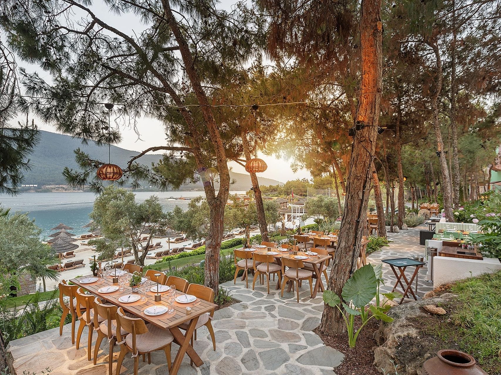 An open-air restaurant at Titanic Luxury Collection Bodrum, nestled among trees with a serene sea view.