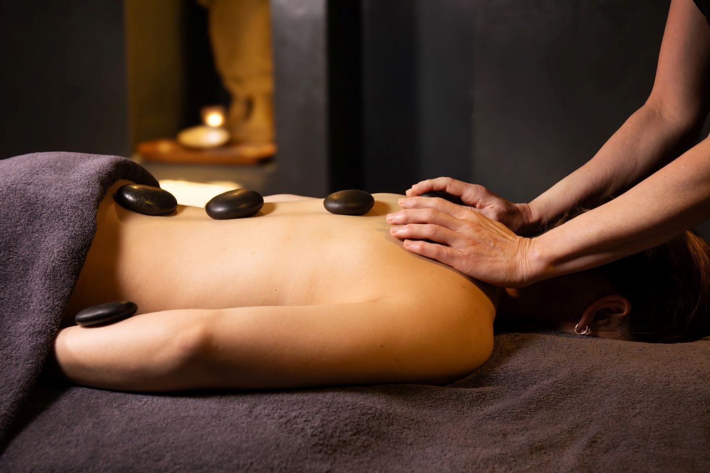 A person receives a relaxing hot stone massage in a spa setting.