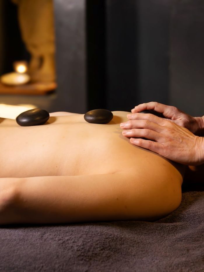 A person receives a relaxing hot stone massage in a spa setting.
