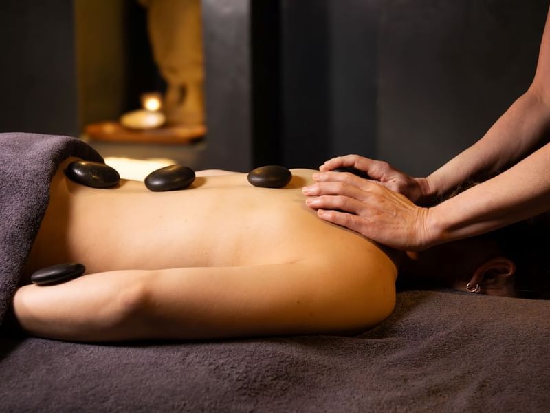 A person receives a relaxing hot stone massage in a spa setting.