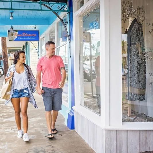 Couple strolling on the side walk while window shopping near Waikiki Resort Hotel by Sono