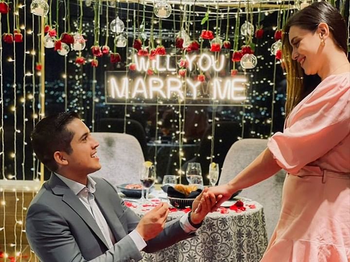Man proposing to a woman with a glowing Will You Marry Me sign in romantic Tangamanga Terrace at Fiesta Americana Travelty