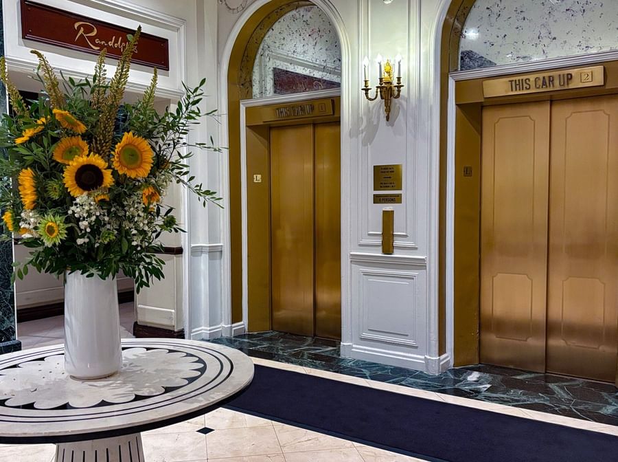 Sunflowers in vase on table in front of elevator doors at Warwick New York.