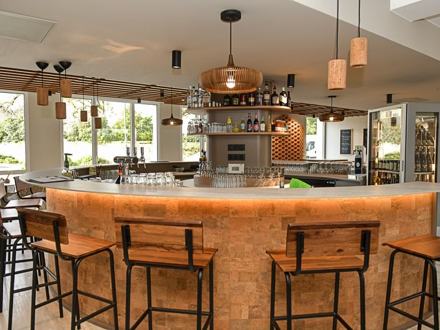 Bar élégant avec tabourets en bois et comptoir lumineux à l'Hôtel Rivella.