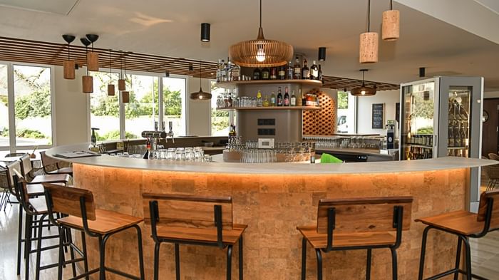 Bar élégant avec tabourets en bois et comptoir lumineux à l'Hôtel Rivella.