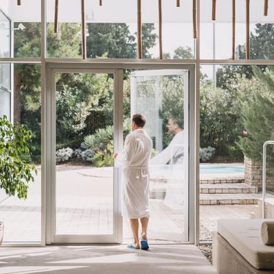 Man in a bathrobe standing by a spa door, Falkensteiner Hotels