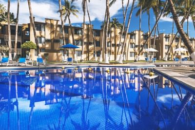 Pool with sunbeds & hotel exterior at Araiza Hotel Palmira