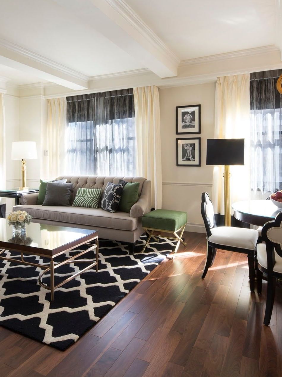 Living area with a large geometric rug with plush seating, and tall curtained windows in Marion Suite at Warwick New York