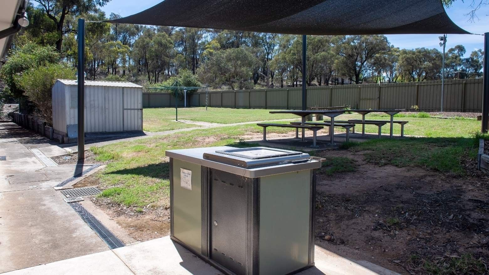 Outdoor picnic area with shaded seating and barbeque at La Trobe University - Orde House.