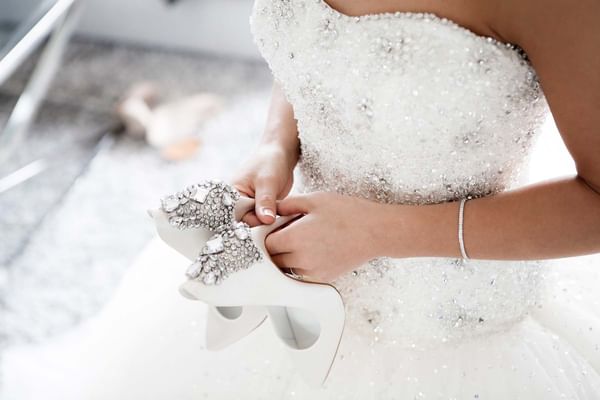 bride in wedding dress holding shoes