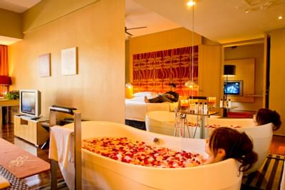 A lady in a bathtub with flower petals