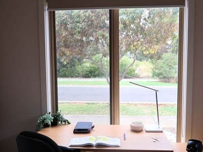 A cozy study area with a desk, open book, and scenic window view at La Trobe University Regional Housing – Melton.
